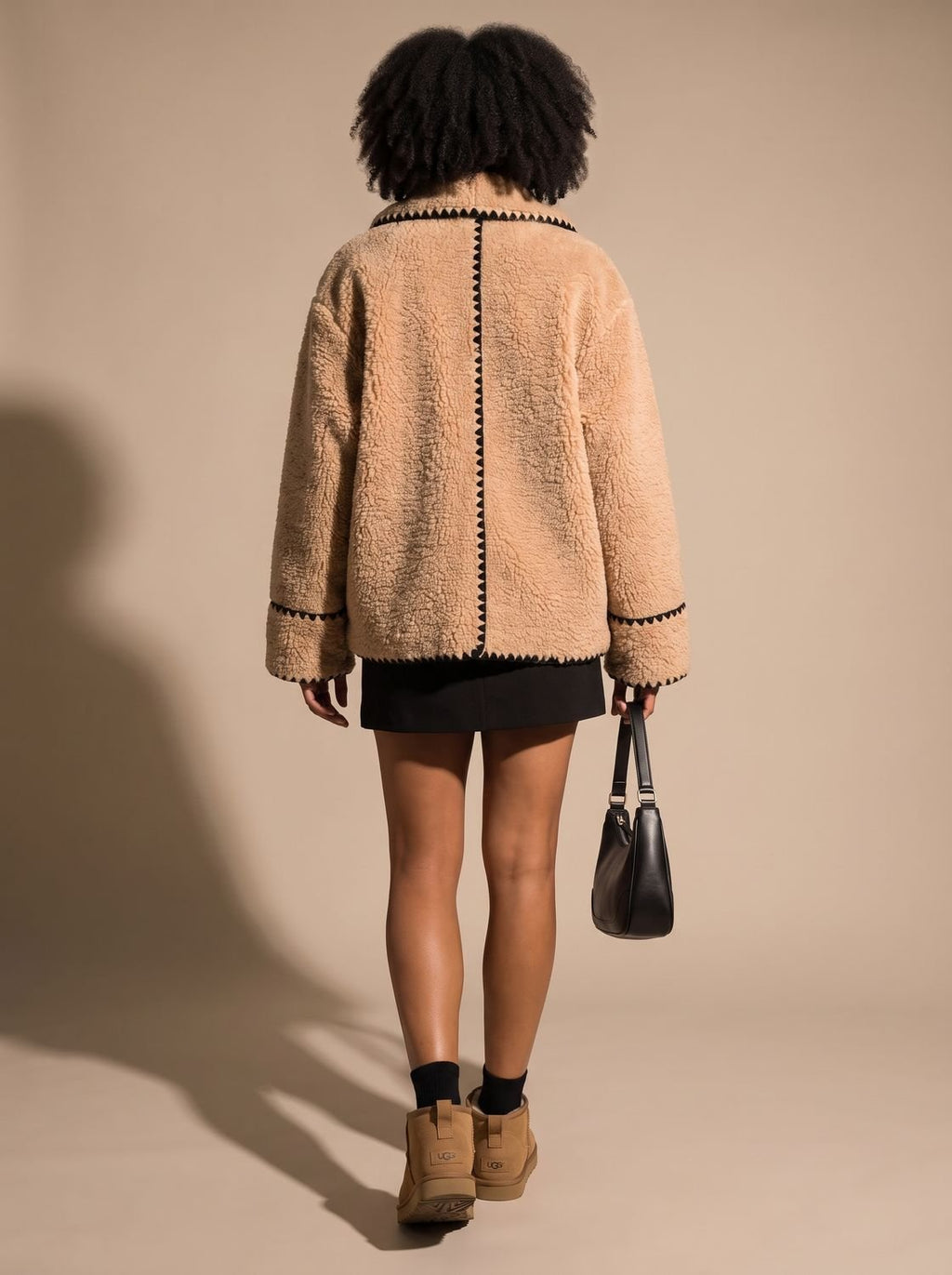 Mujer luciendo el abrigo teddy fleece corto sobre look casual