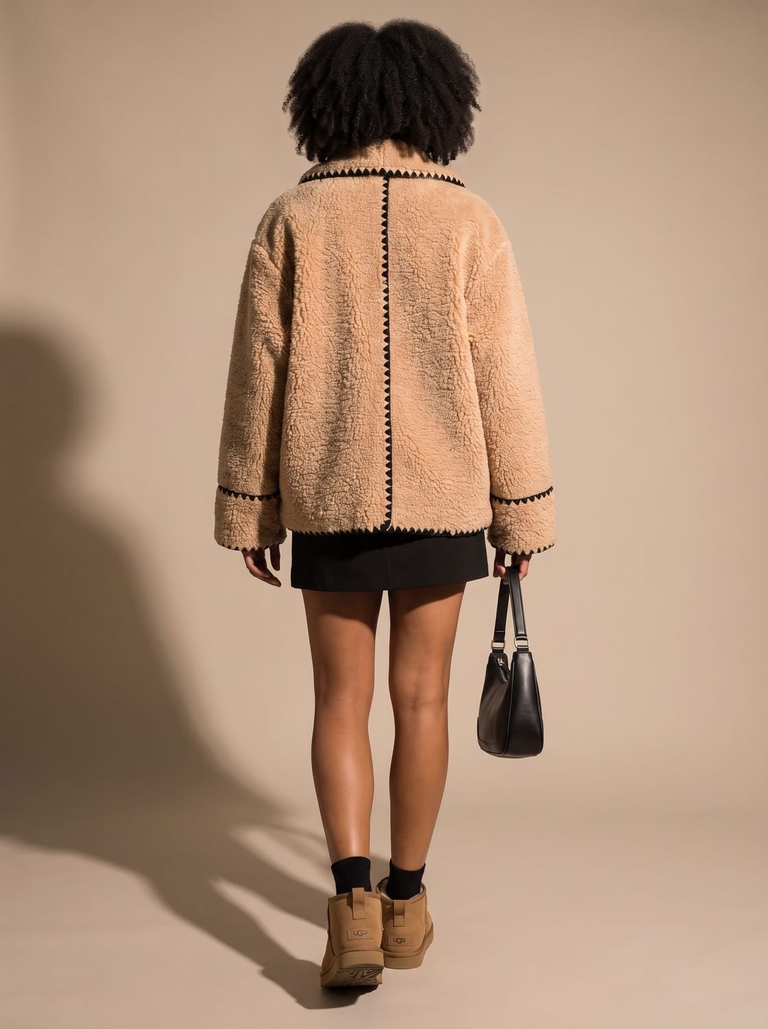 Mujer luciendo el abrigo teddy fleece corto sobre look casual