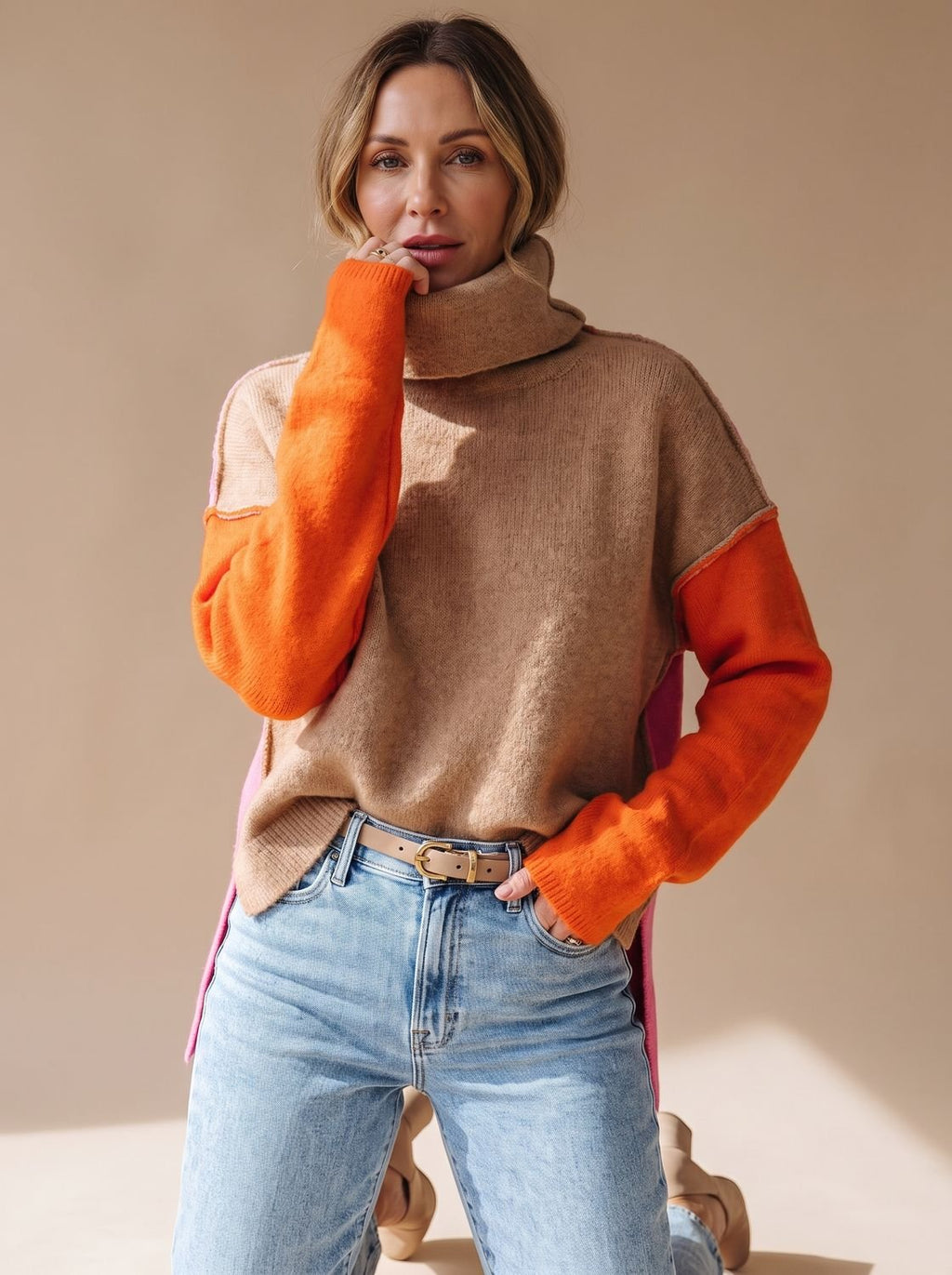 Mujer con jersey de cuello alto color block en camel, naranja y rosa