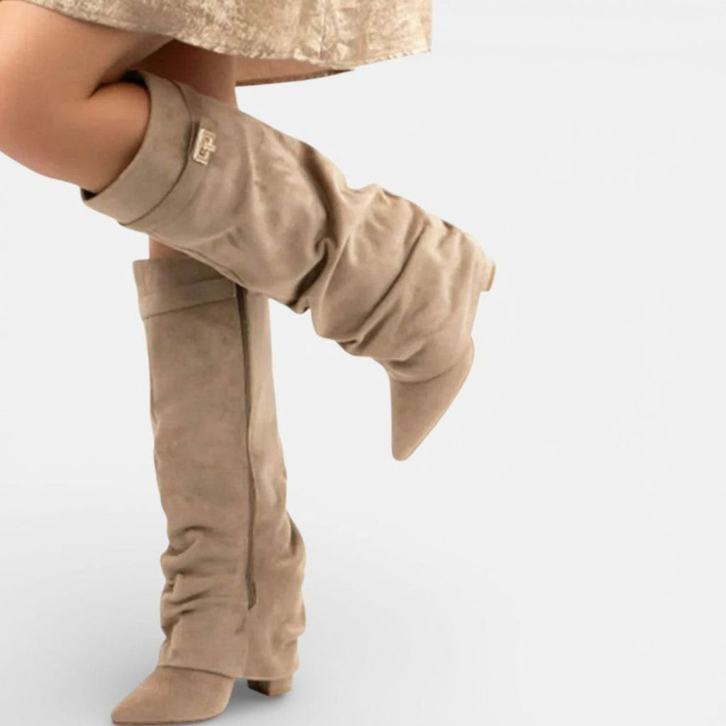 Vista lateral de botas altas con hebilla dorada y caña fruncida hasta la rodilla