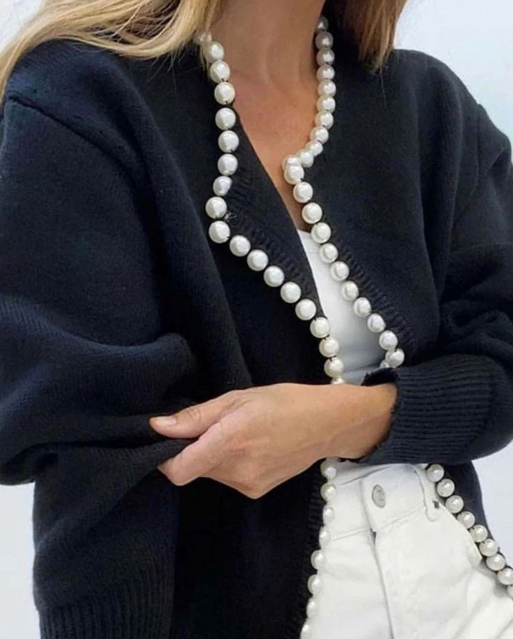 Mujer con cárdigan de punto abierto y detalle de perlas en el borde delantero