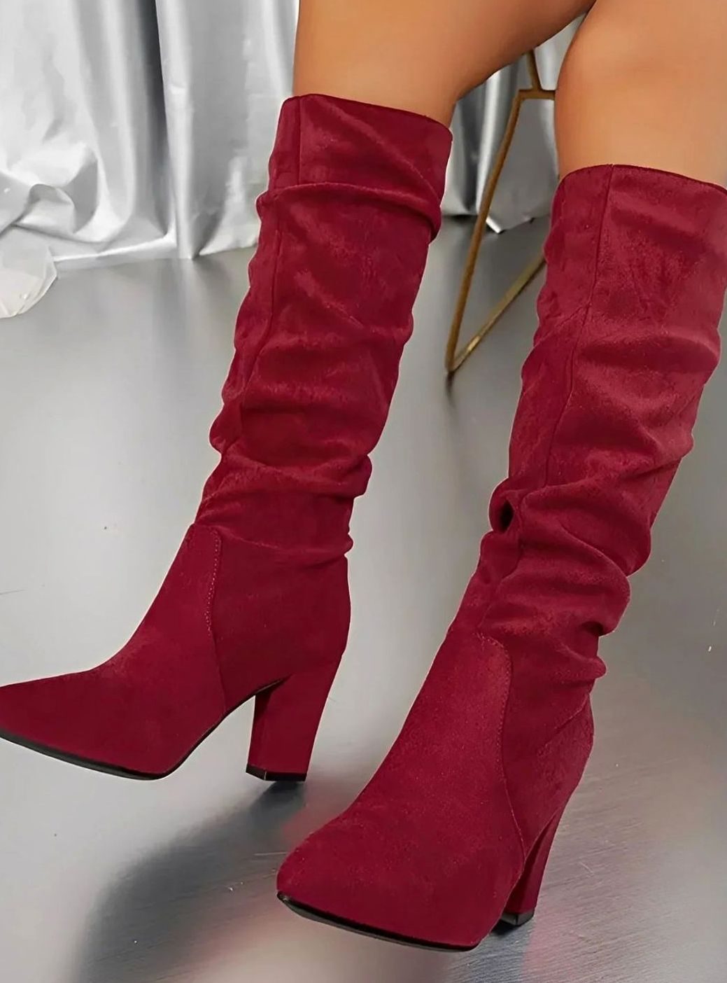 Mujer luciendo botas altas fruncidas con vaqueros y jersey