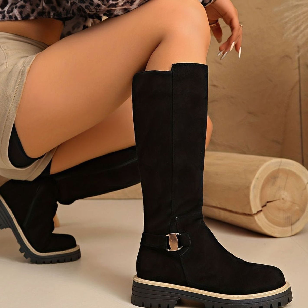 Vista lateral de botas altas de ante con hebilla decorativa en el tobillo