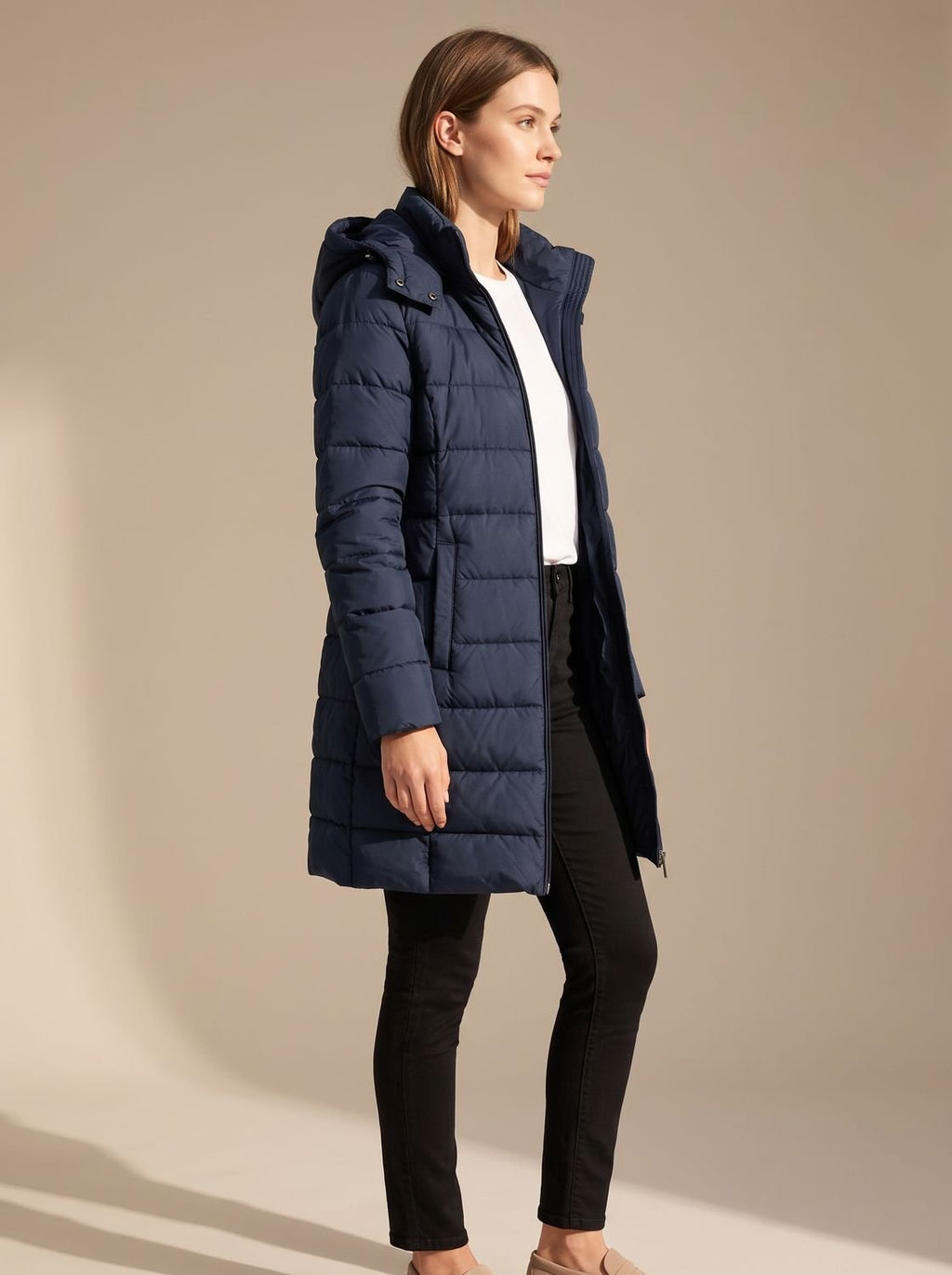 Mujer con plumífero largo con capucha en look de invierno
