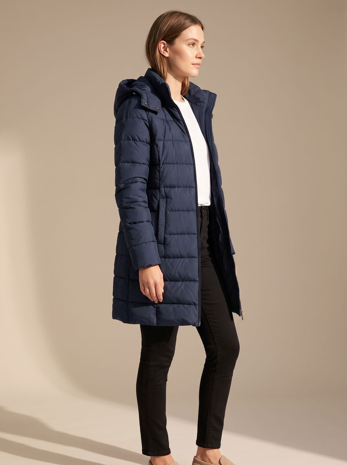 Mujer con plumífero largo con capucha en look de invierno